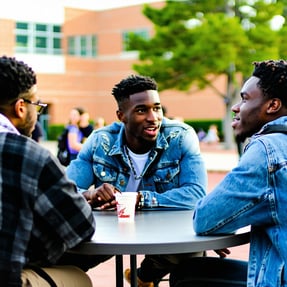 young Black men table talk on campus