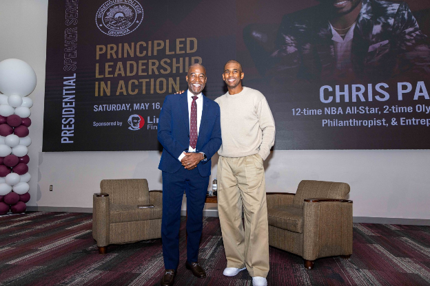 President Bowman and Chris Paul standing together in front of the Principled Leadership in Action speaker series banner