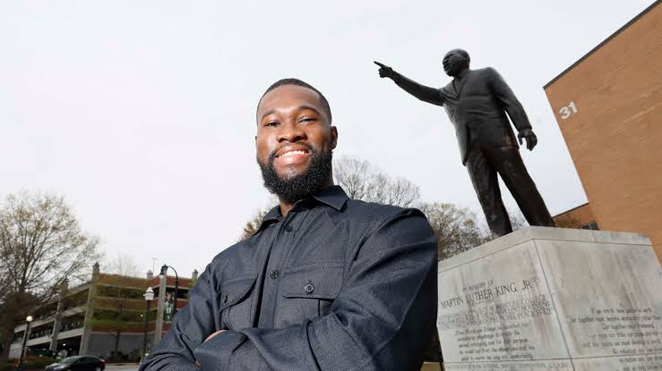 Rhodes Scholar Aniaba N'guessan standing before the Martin Luther King Jr. statue on campus