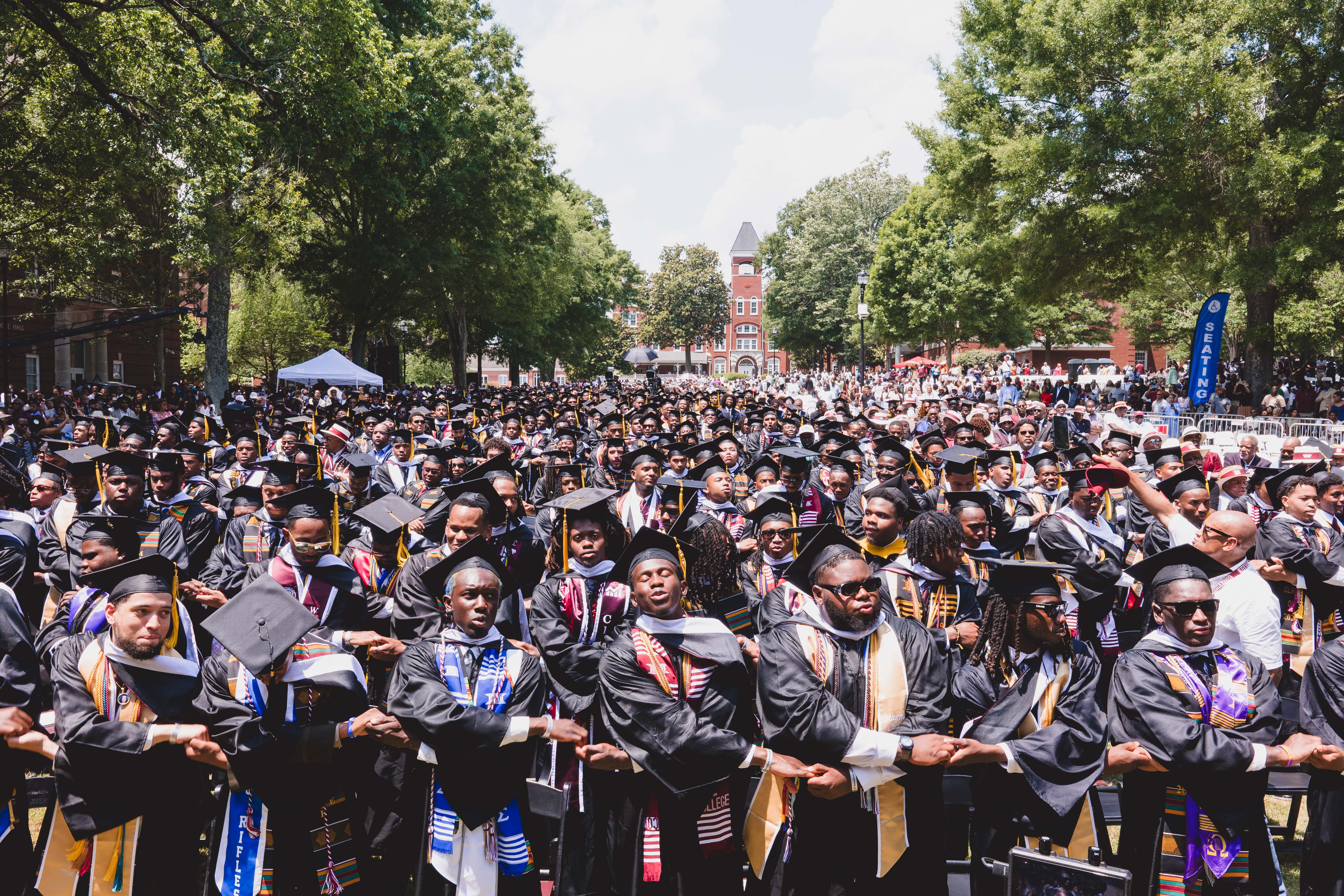 Graduates in caps and gowns linking arms on the Morehouse quadrangle at Commencement