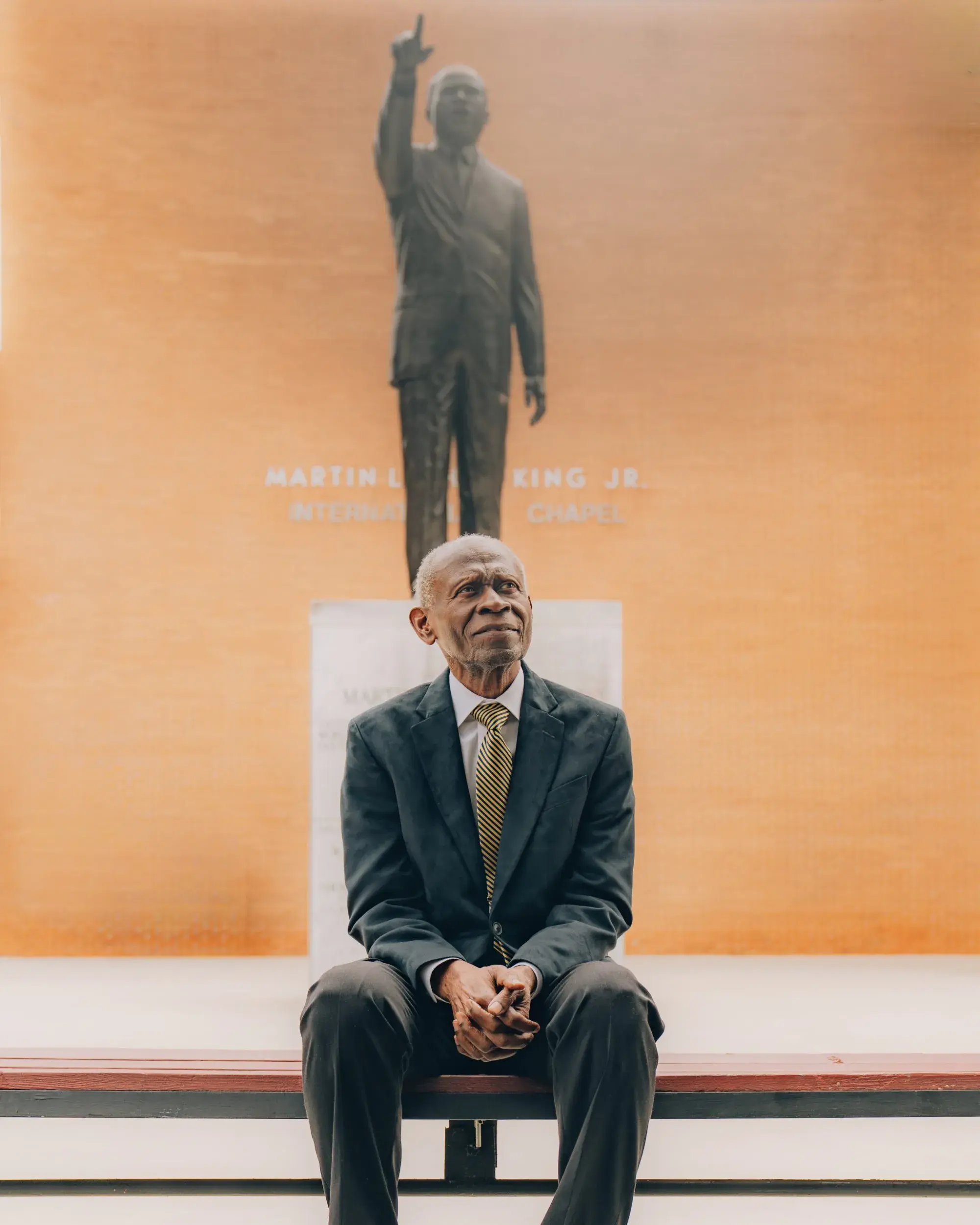 Rev. Dr. Lawrence Carter Sr. seated before the Martin Luther King Jr. statue at King Chapel