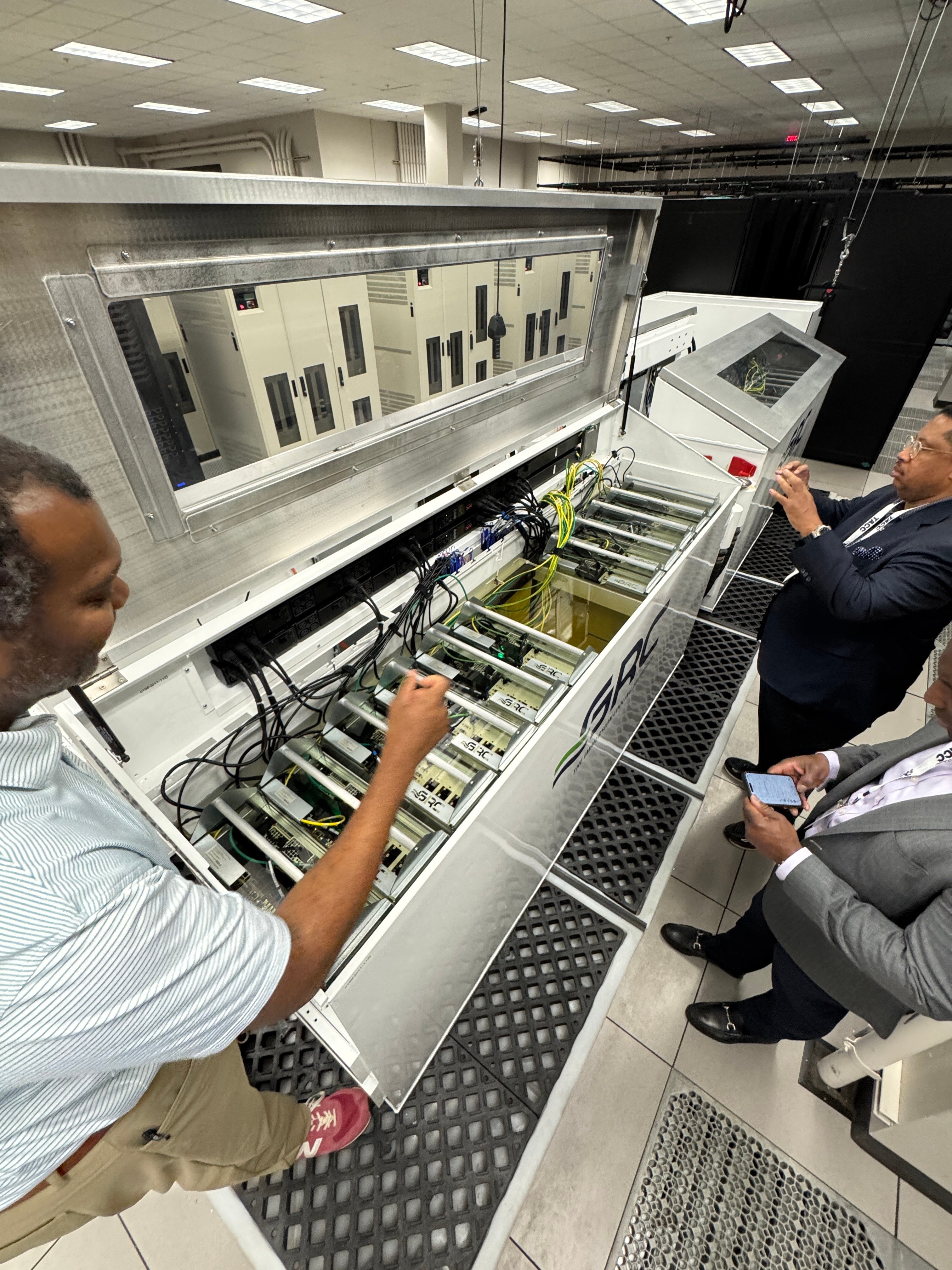 Faculty inspecting immersion-cooled compute nodes in a data center during a Horizon site visit